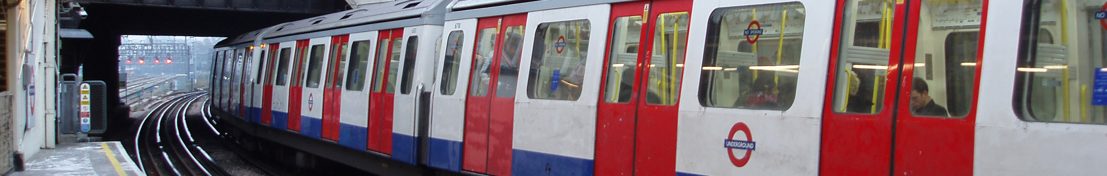 A long London underground train sits waiting at a platform